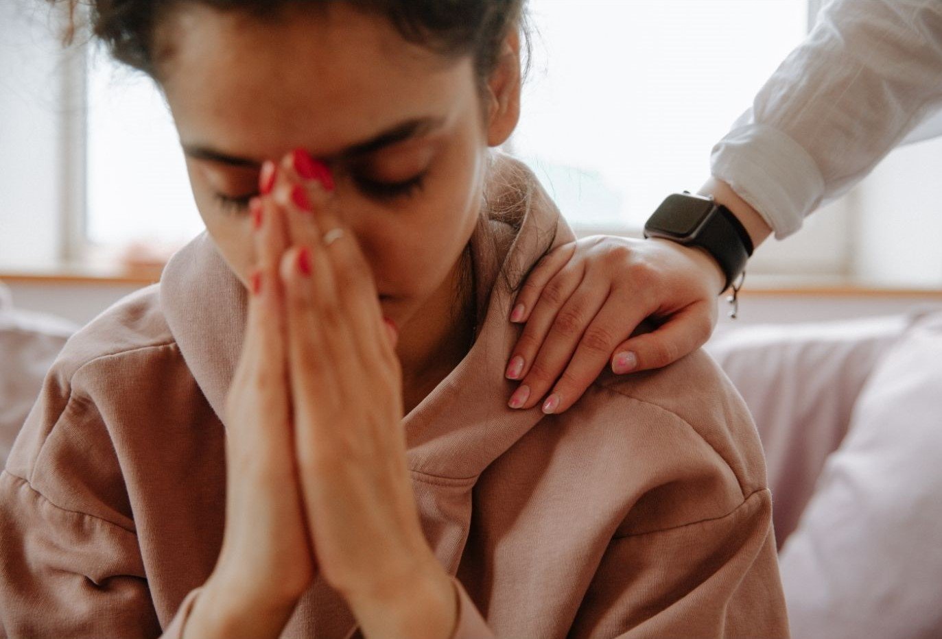 An image of a distressed person with a comforting hand on their shoulder.