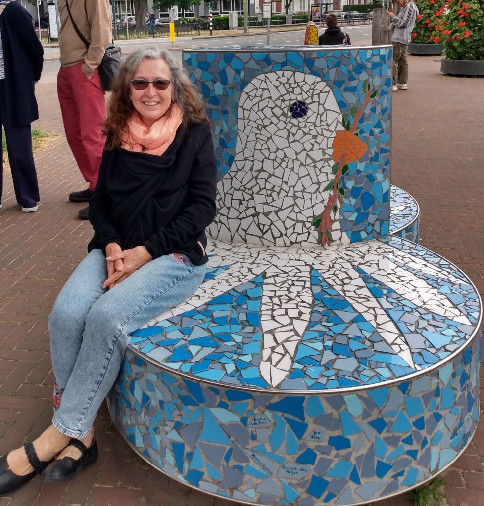 Pamela sitting on a mosaic seat in Amsterdam.