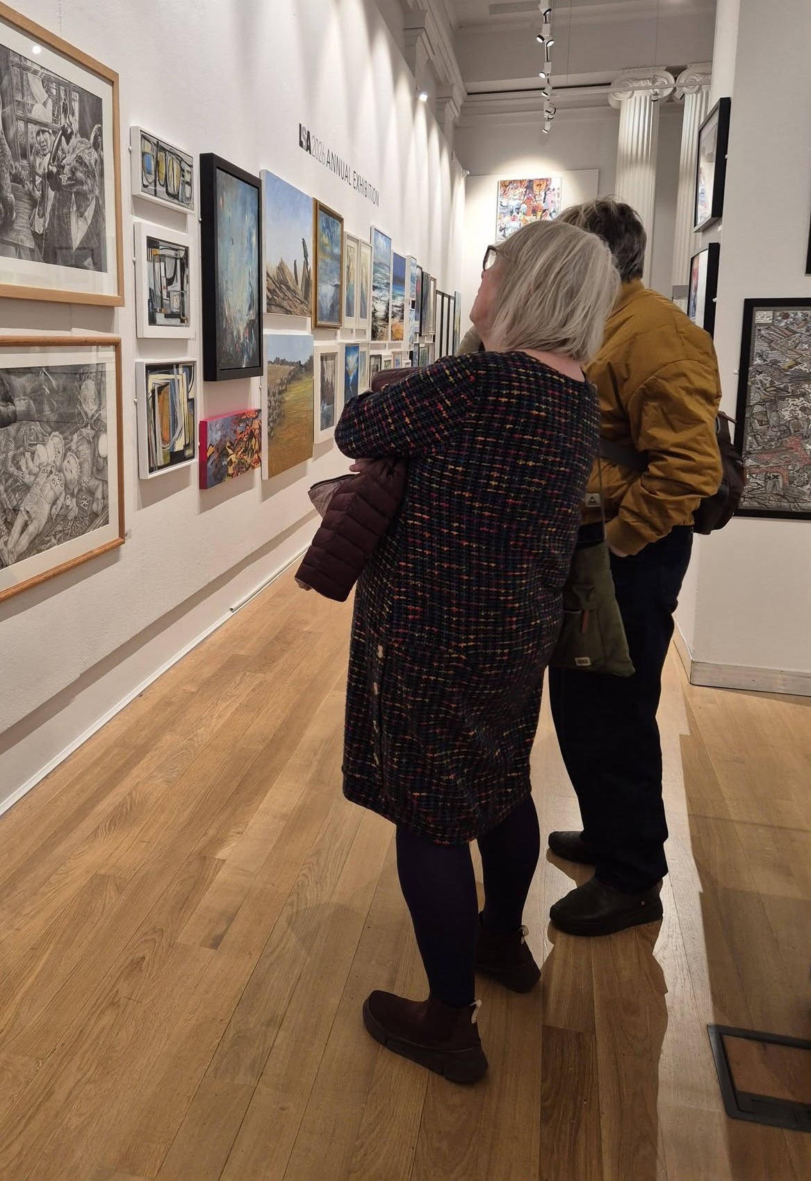 Two members of the Discovery Circle viewing a wall of paintings at the New Walk Museum and Art Gallery.