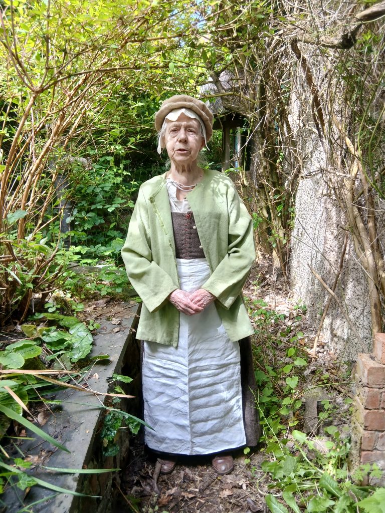 Alison Coates dressed in Tudor clothes consisting of bodice, long skirt, apron and hat.