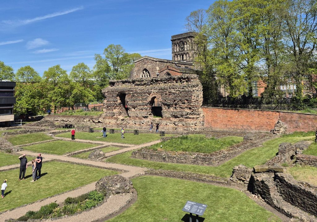 A photo of the Jewry Wall with St Nicholas Church behind and the ruins of the rest of the baths in front.