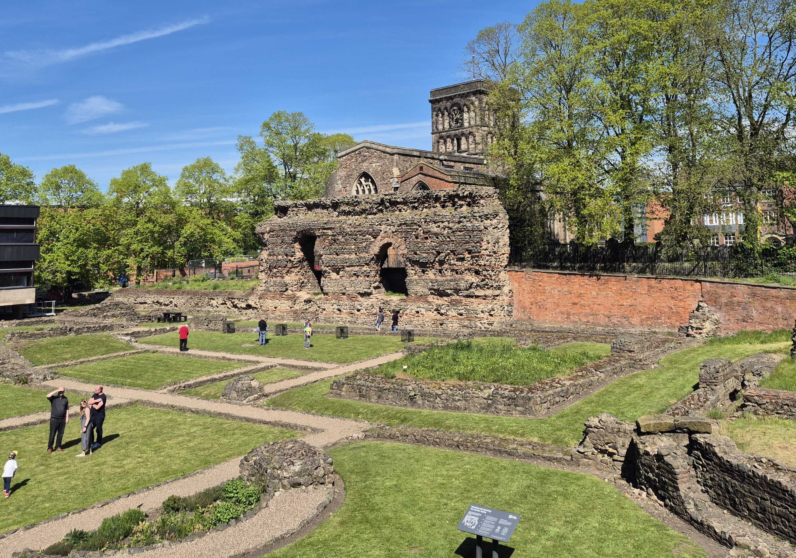 A photo of the Jewry Wall with St Nicholas Church behind and the ruins of the rest of the baths in front.
